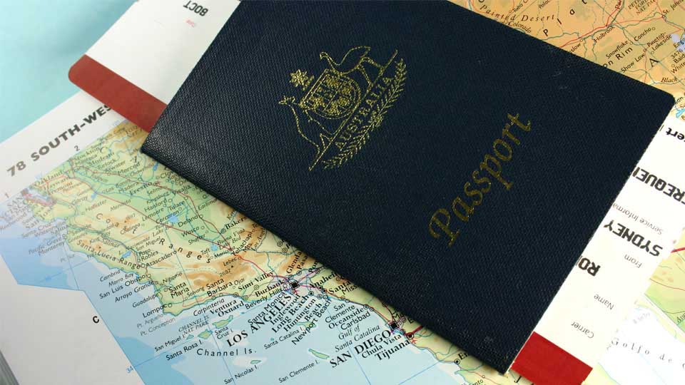 Australian passport holding a plane ticket atop a map of the west coast of the USA.