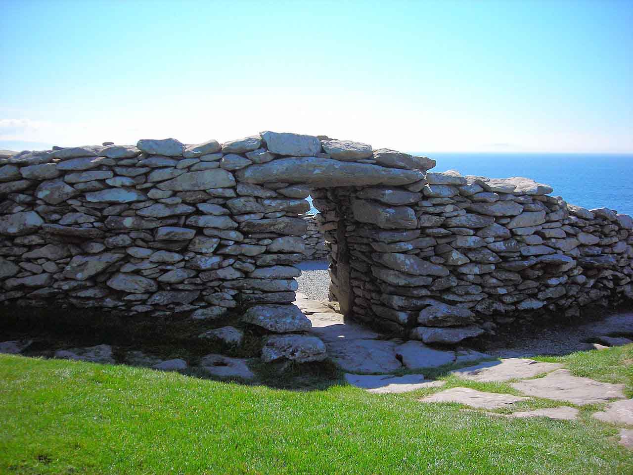A stone piling wall with a doorway by the sea