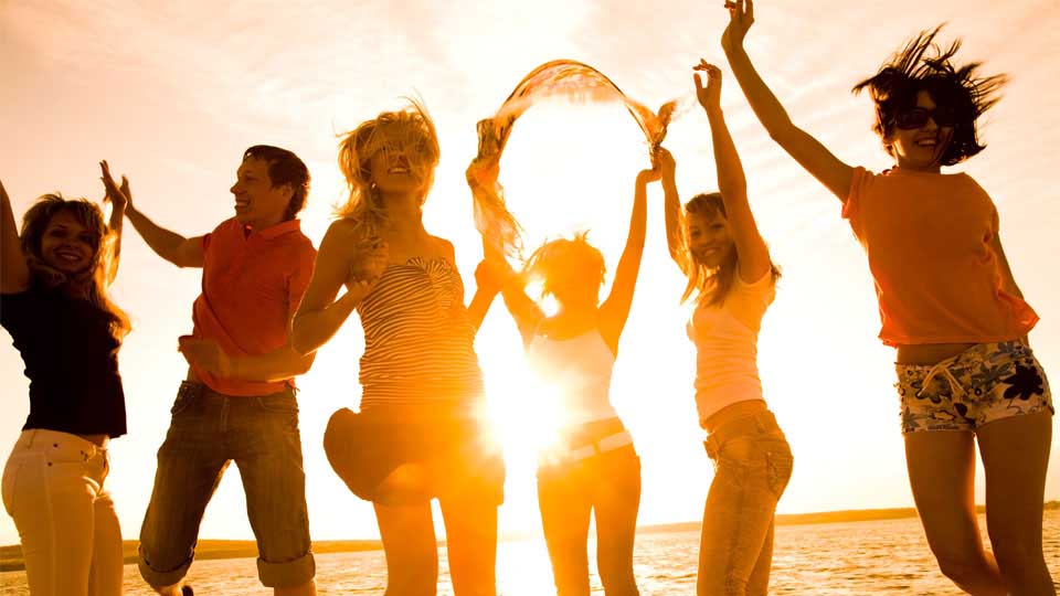 Happy People Dancing On A Beach At Sunset