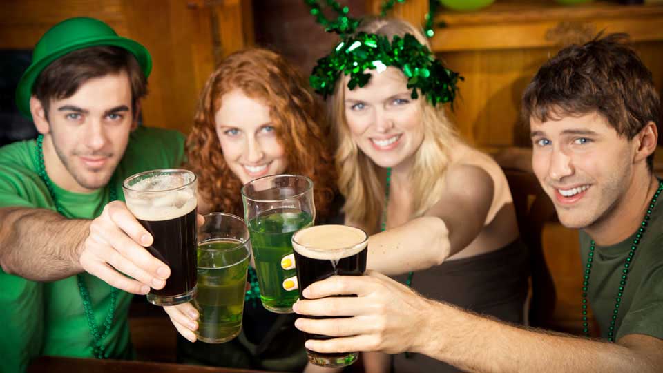 Two Couples Wearing Green and Drinking Green Beer in a Pub