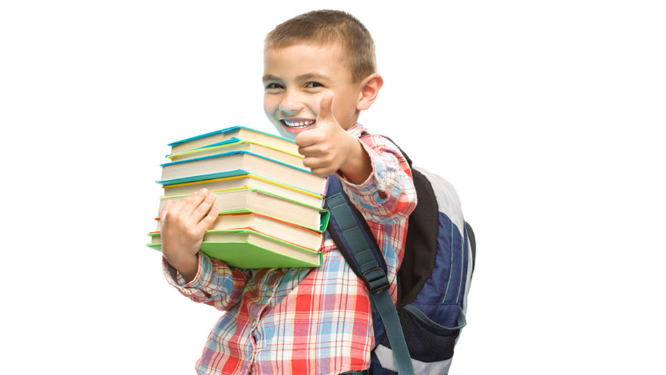 Happy schoolkid carrying a big stack of books.