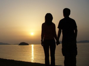 A couple holding hands by the sea at sunset