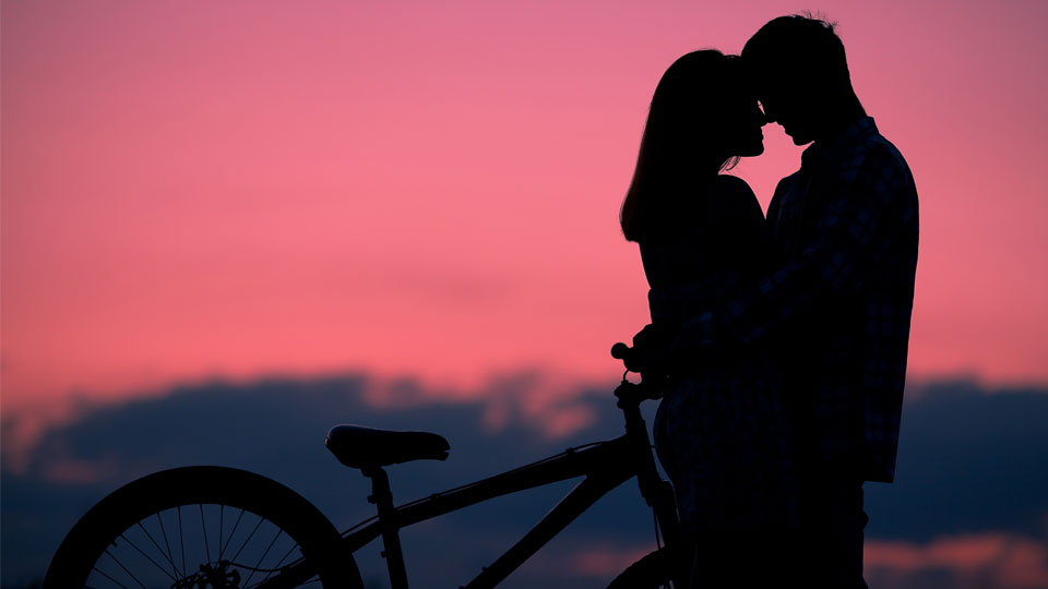 silhouette of a happy couple beside a bicycle