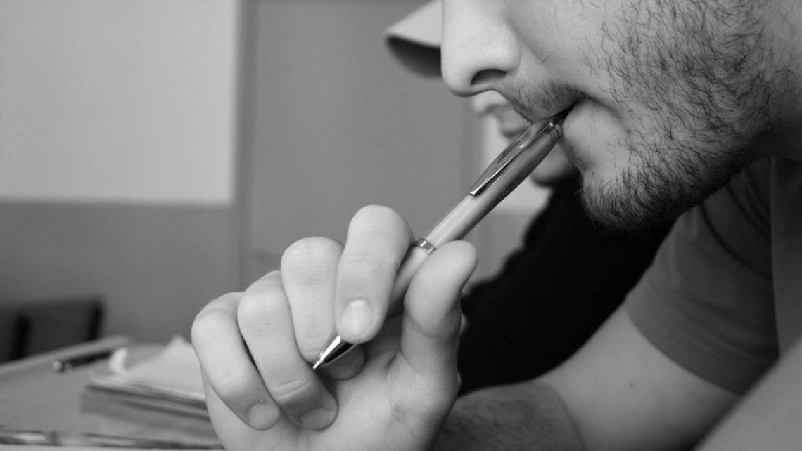 A man thinking hard and chewing a pen