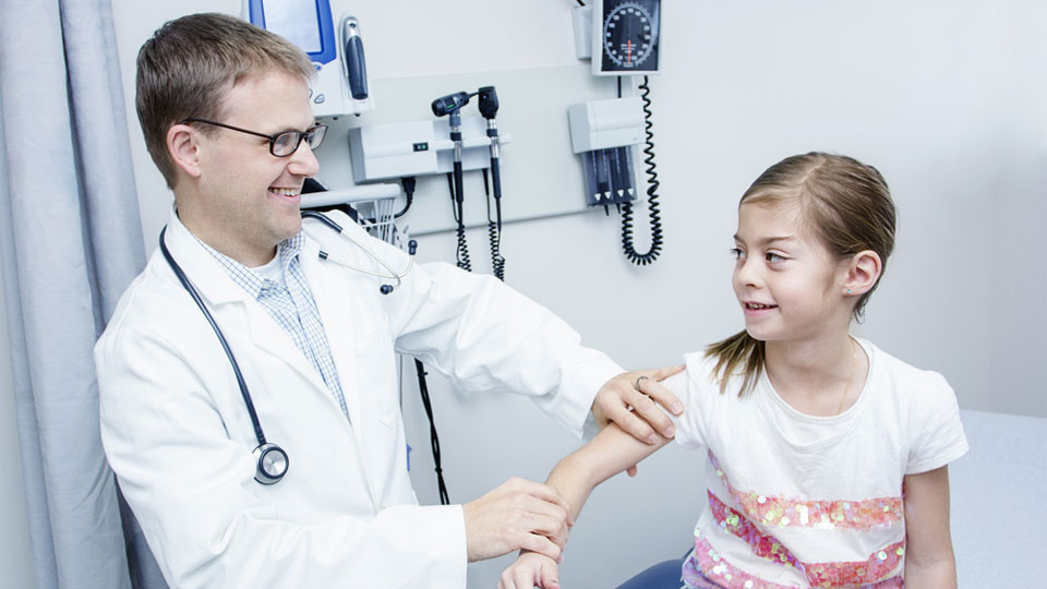 A doctor examining a young girl's arm