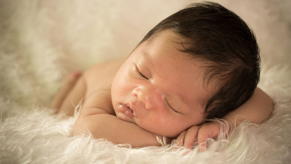 A cute Thai baby napping on a fur carpet