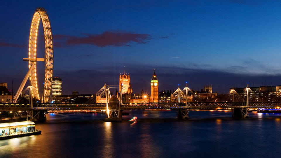 The London skyline with the London Eye in foreground, lit up for night